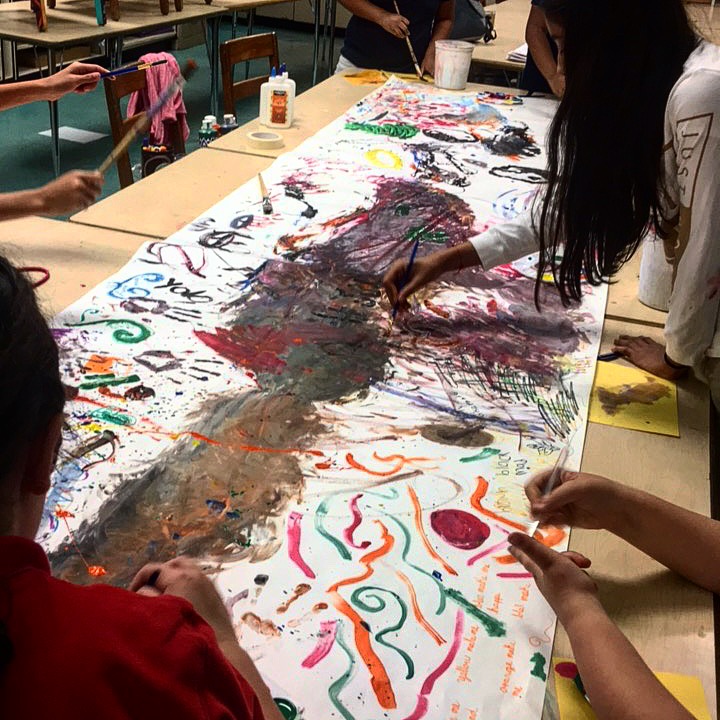 Students in A4L's after-school program at Feinberg Fisher K-8 Center work on a collaborative mural with Teaching Artists Jean Michael Vissepio Ocasio.